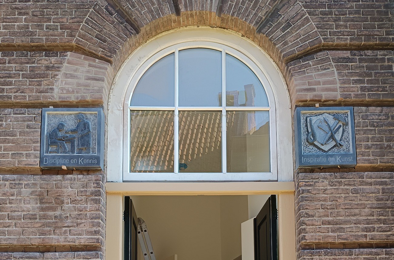 Gevelstenen geplaatst aan de gevel van de Van Heutzschool