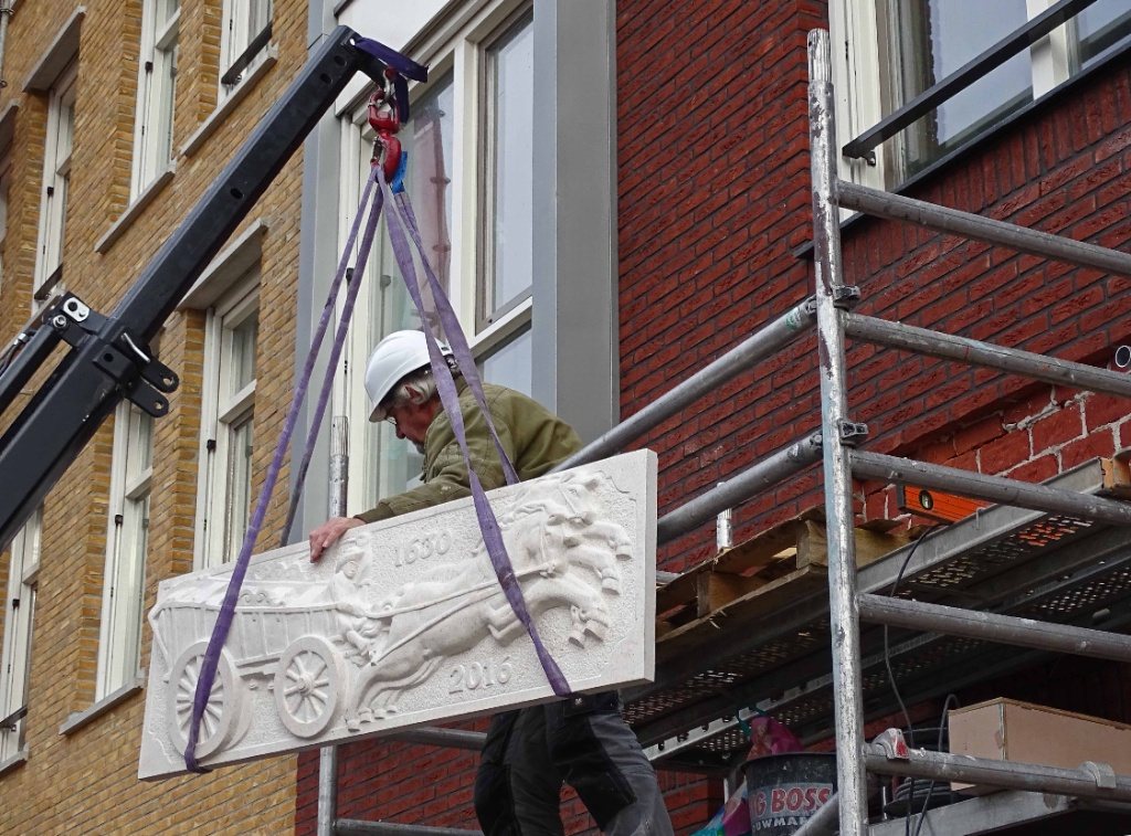 Plaatsing van een grote handgehakte gevelsteen aan een pand