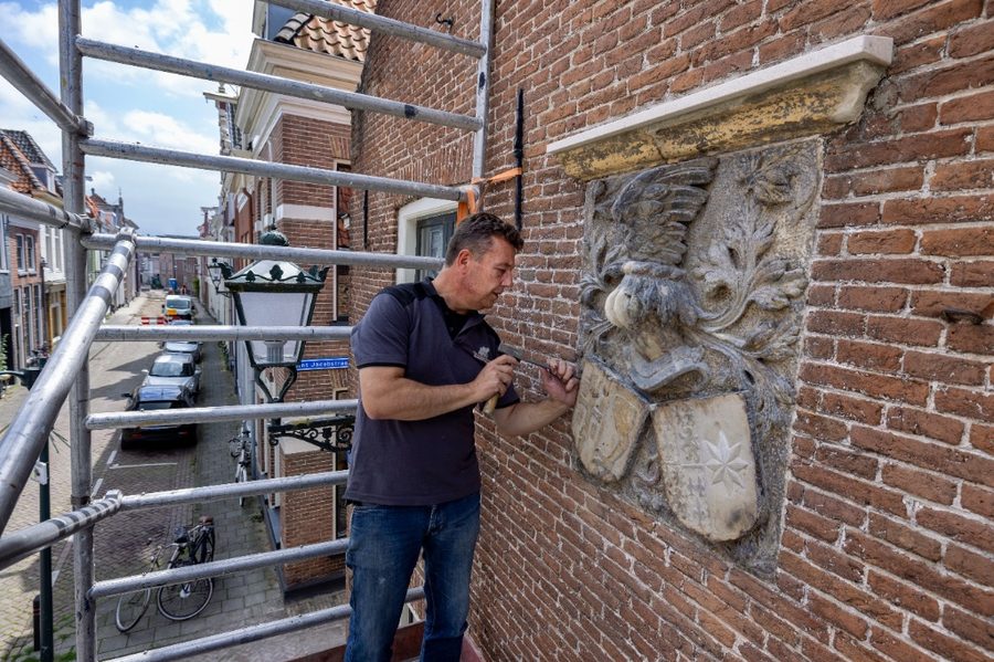 Gevelsteen vóór restauratie aan een bakstenen gevel